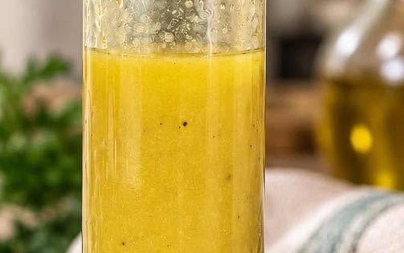 Bouteille de vinaigrette maison dorée, persil en arrière-plan